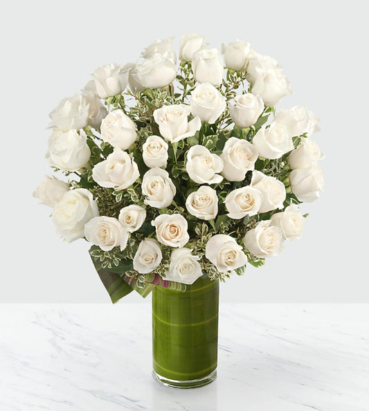 48 stems of 24-inch premium long-stemmed white roses, exotic foliage and a superior 10-inch clear glass cylindrical vase.