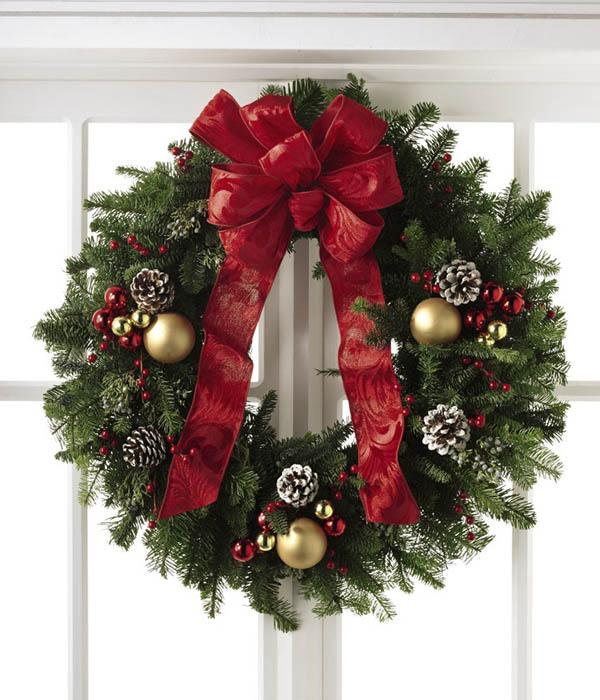 With a base consisting of fresh and fragrant Christmas greens, this wreath is bedecked with white tipped pine cones, shining red and gold glass holiday balls, and clusters of berries, culminating in a standout red bow at the top. 22 INCHES IN DIAMETER