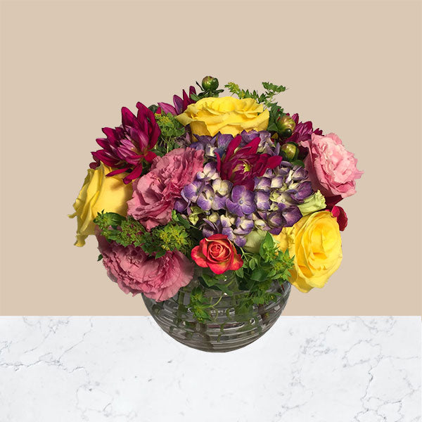 Our glass bowl is filled with bountiful blooms including, hydrangea, lisianthus, roses and dahlia.