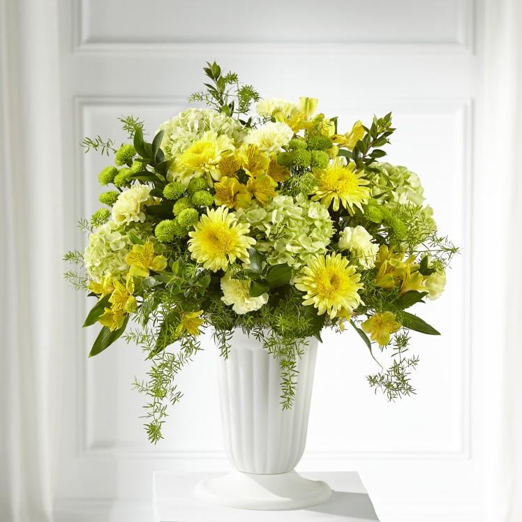 green and yellow blooms of hydrangeas, Cremon mums, alstromerias, green button pom poms, carnations, and lush greens in all white pedestal