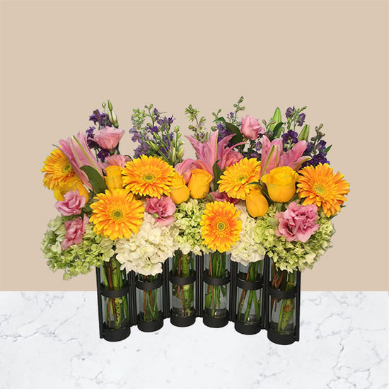 Beautiful, freshly picked spring flowers including roses, lisianthus, roses, gerberas and hydrangea blooms fill this unique snake vase, to create a long, full blooming garden,