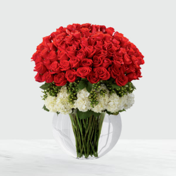 Includes: 75 stems of red 24-inch premium long-stemmed roses, 7 stems of white hydrangea, 12 stems of green hypericum berries, and a superior clear glass pillow vase.